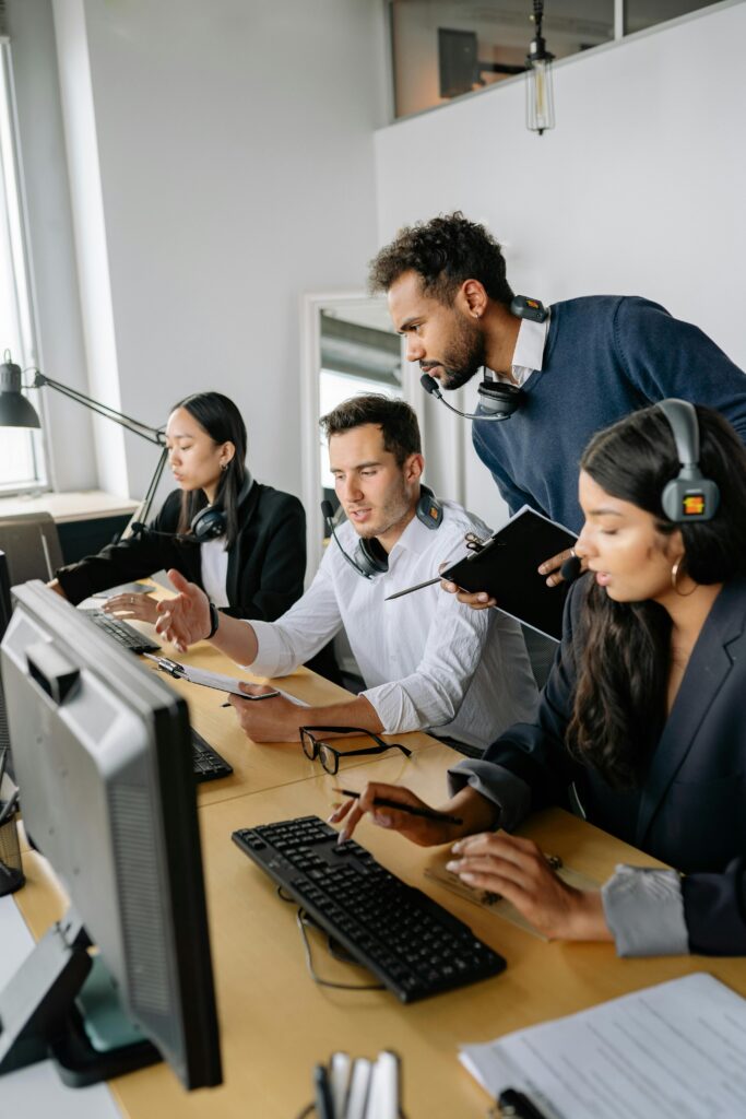 A diverse group of call center employees working and collaborating at desks with headsets in a modern office.